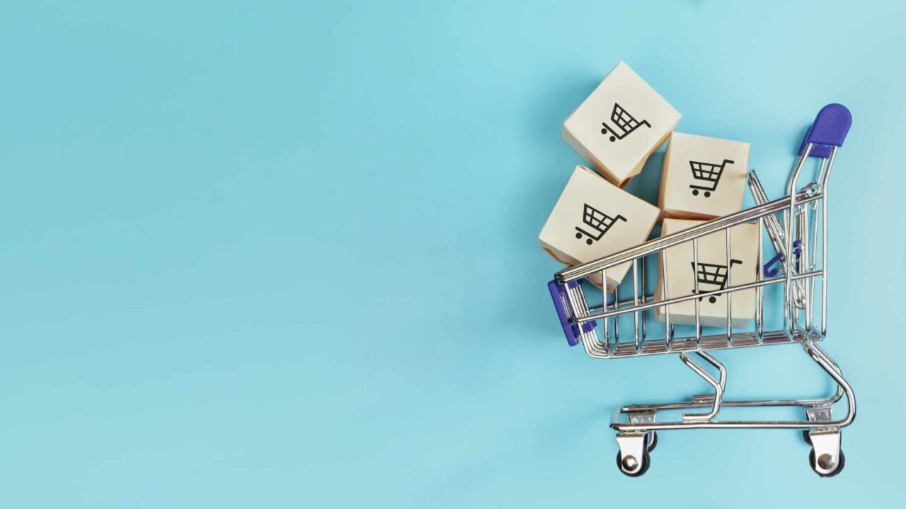 Boxes in a shopping cart on blue background. Concept: online shopping, e commerce and delivery of goods. Copy space.